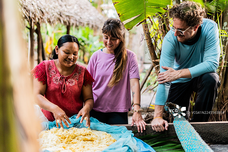 哥伦比亚瓜伊尼亚，游客和一位原住民妇女正在准备卡萨贝（亚马逊传统面包）。图片素材