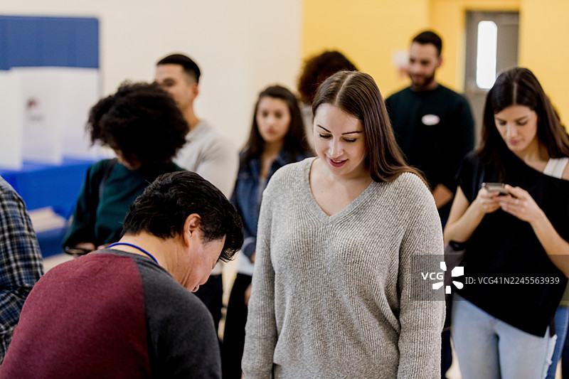 一群不同背景的人在室内排队，进行着日常活动。图片素材