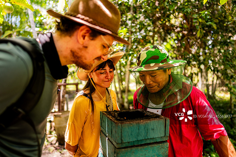 游客与当地人在热带森林中了解养蜂图片素材