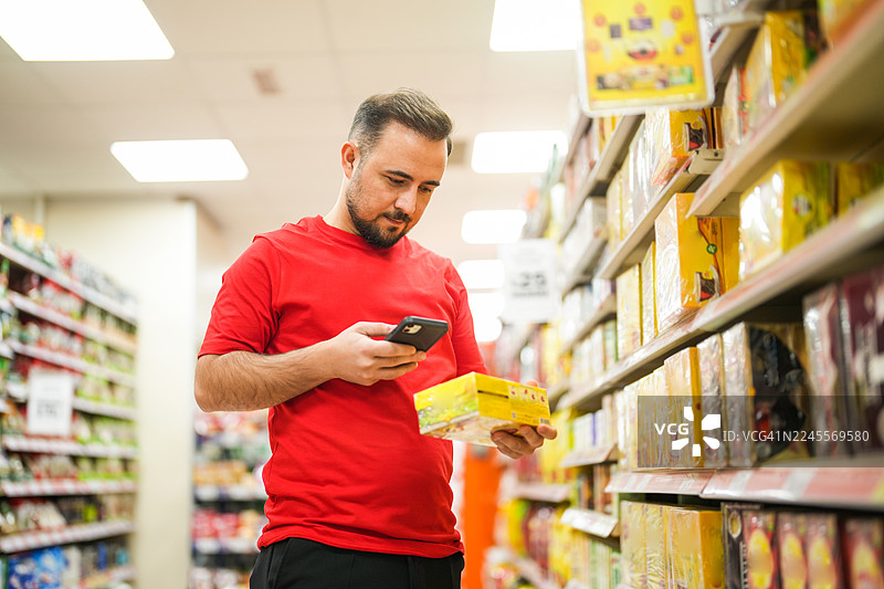 顾客在超市过道里用智能手机扫描商品图片素材