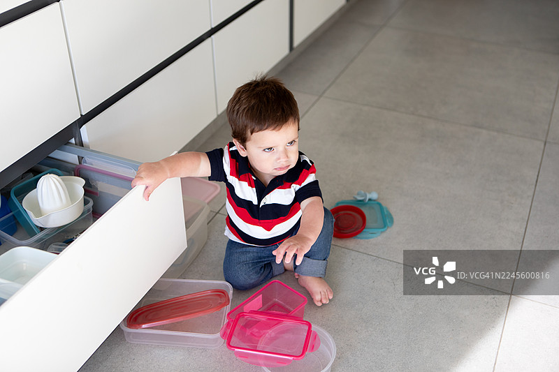 淘气的一岁宝宝在玩保鲜盒图片素材