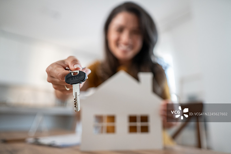 女子手持房屋钥匙和房屋模型图片素材