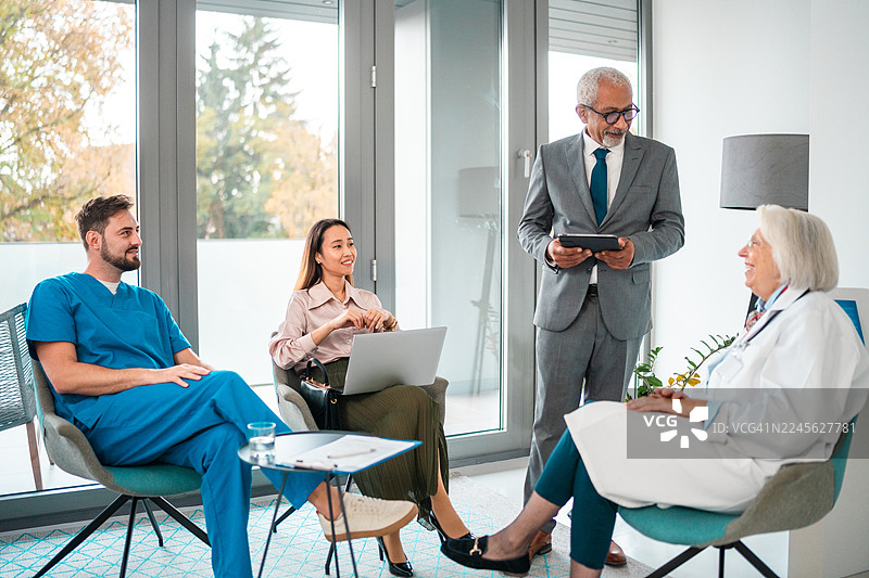 经验丰富的多民族男性经理与多元化的医院团队讨论工作流程策略图片素材