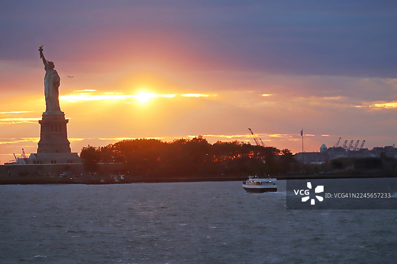 日落时自由女神像的壮丽景色/纽约市天际线/美国图片素材