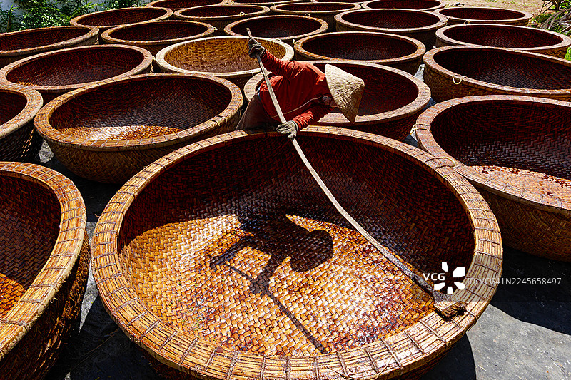 工人给竹编的船进行防水处理图片素材