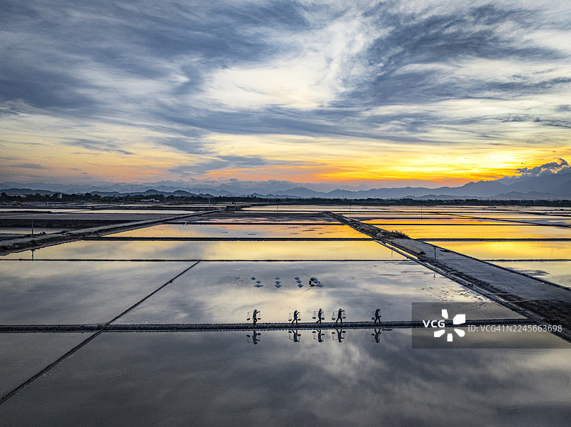 日落时分，盐业工人走过盐田图片素材