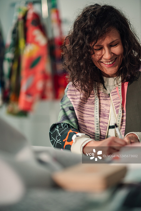 女设计师在创意工作室微笑着绘制时装草图图片素材