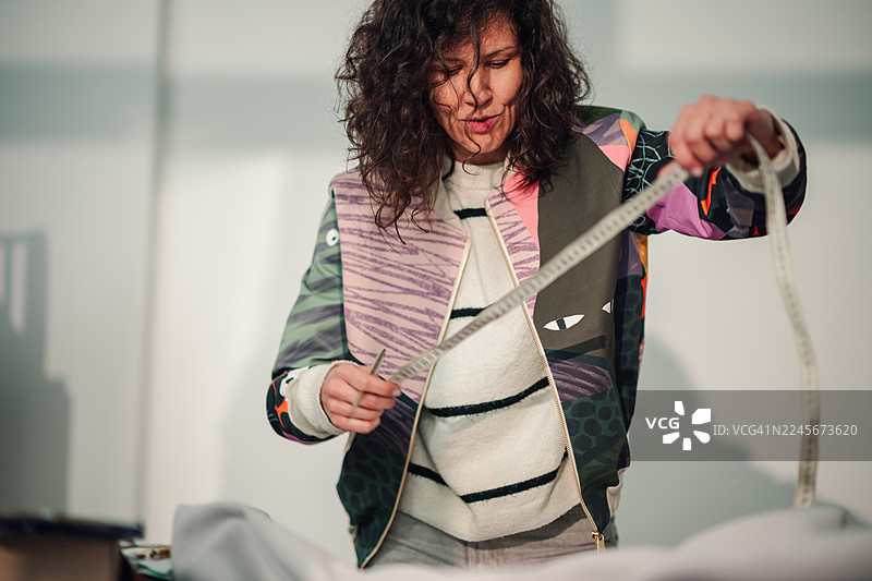 时尚设计师在创意工作室测量布料图片素材