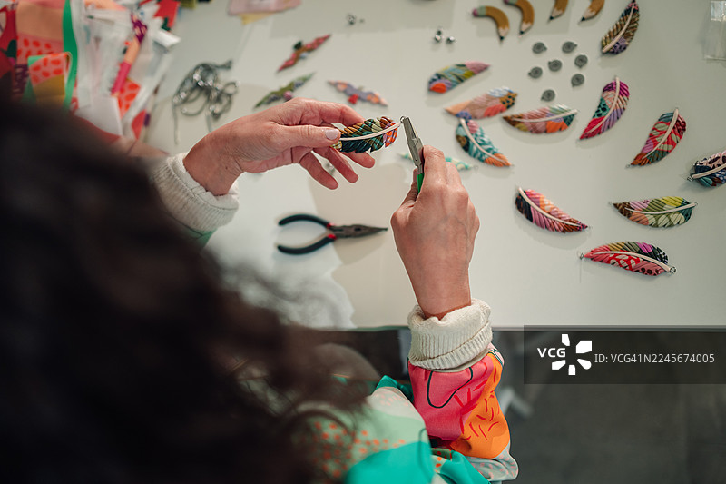 一个人用色彩鲜艳的布羽毛制作手工珠宝图片素材