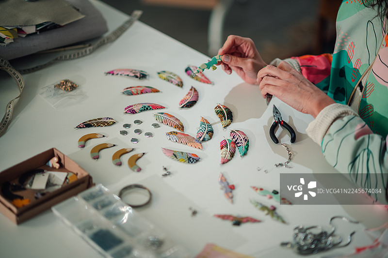 女子制作手工饰品，其中包含色彩鲜艳的羽毛耳环图片素材