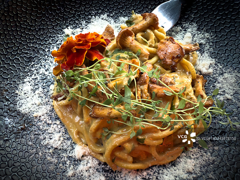 自制意大利宽面配新鲜的鸡油菌，以花朵装饰。图片素材