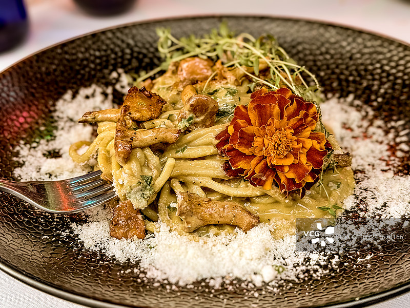 自制意大利宽面配新鲜的鸡油菌，并饰以花朵。图片素材