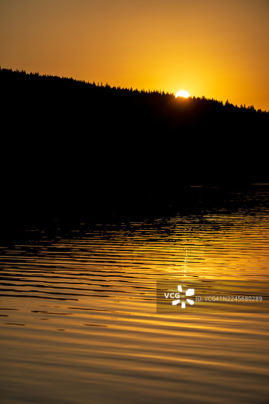 芬兰北部森林落日倒影在平静的水面上图片素材
