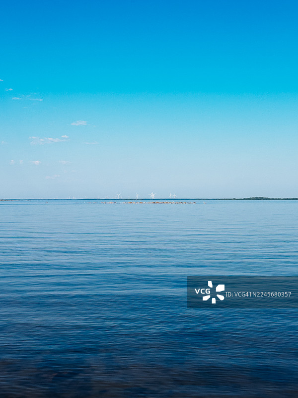 晴朗天空下的平静蓝色波罗的海，远方是芬兰西北部海岸的风力涡轮机图片素材