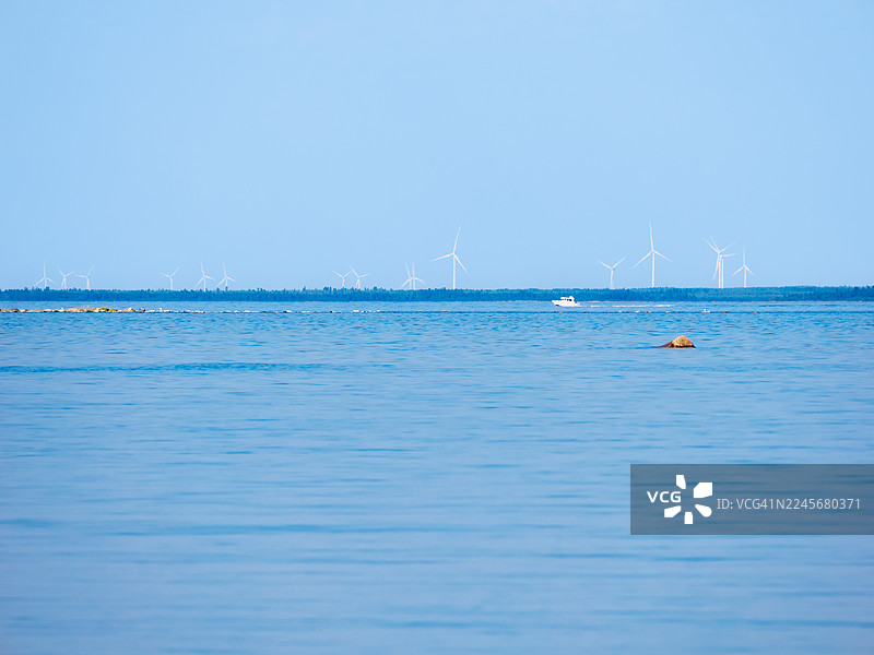 船只在波罗的海平静的海面上经过远处的风力发电场，位于芬兰西北部沿海地区图片素材
