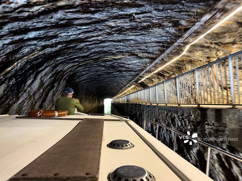 男子在驳船穿过岩石隧道时拍照图片素材