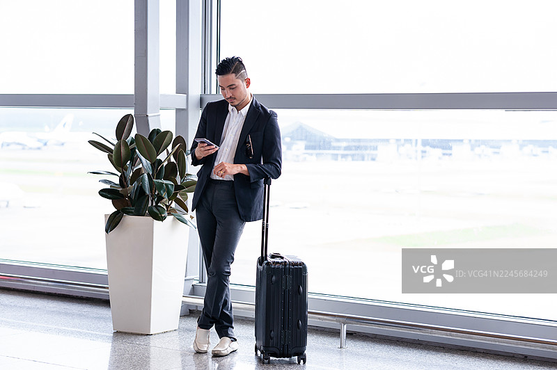 亚洲商务人士在机场航站楼使用智能手机图片素材