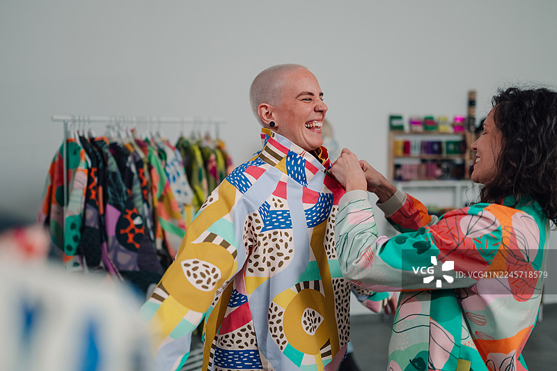 女性朋友们享受购物，试穿色彩鲜艳的服装图片素材