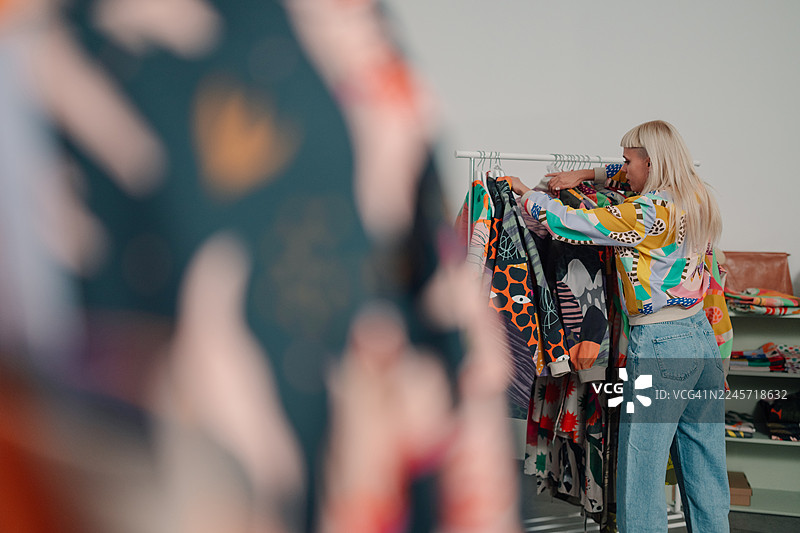 女子在商店选购色彩缤纷的时尚服装图片素材