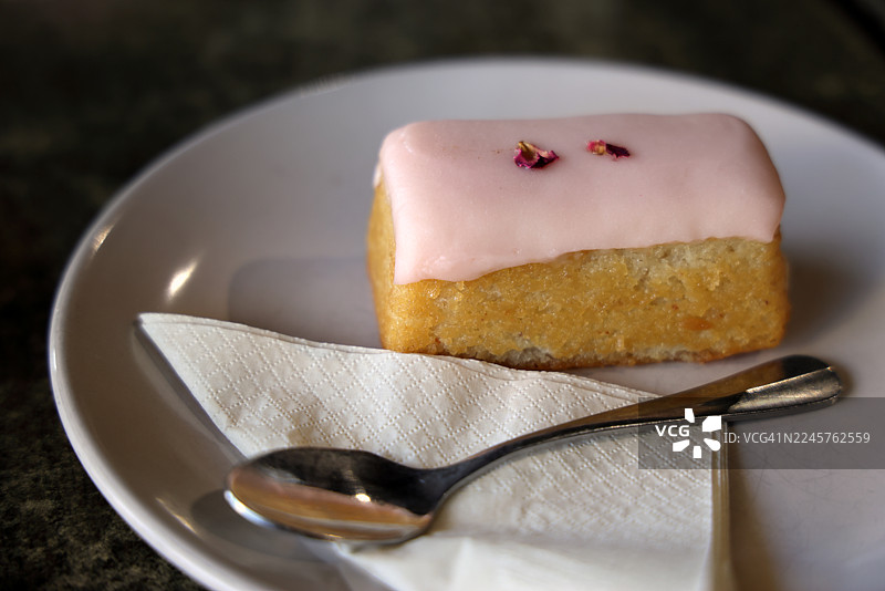 盘子里放着单独包装的柠檬糖霜蛋糕条，旁边还有一把茶匙和一张纸巾图片素材