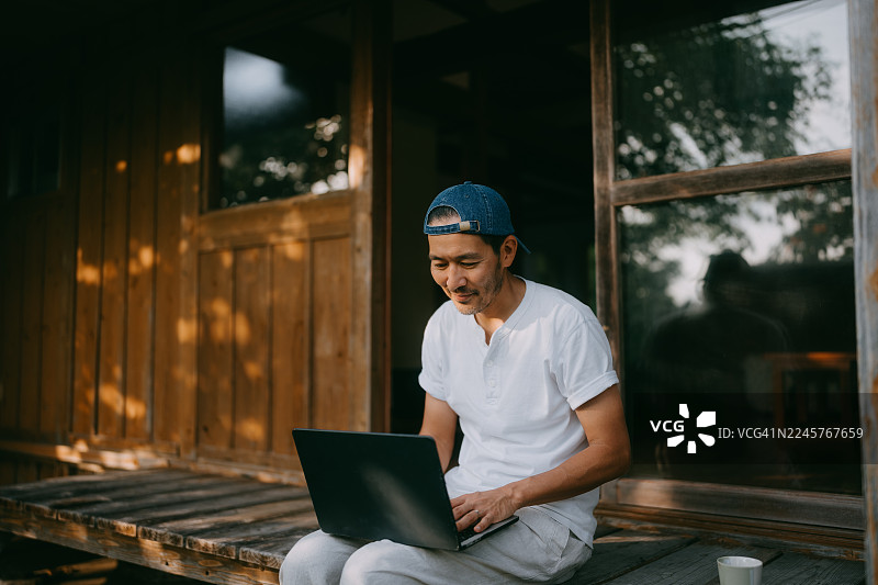 日本房屋廊下（缘侧）上使用笔记本电脑工作的男子图片素材