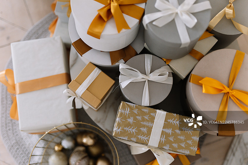 圣诞节礼物盒堆成大堆，用丝带装饰，在十二月家中装饰的圣诞树旁，节日礼物概念。图片素材