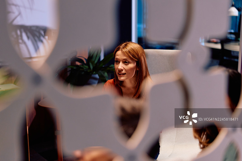 红发女子在现代办公室会议中交谈图片素材