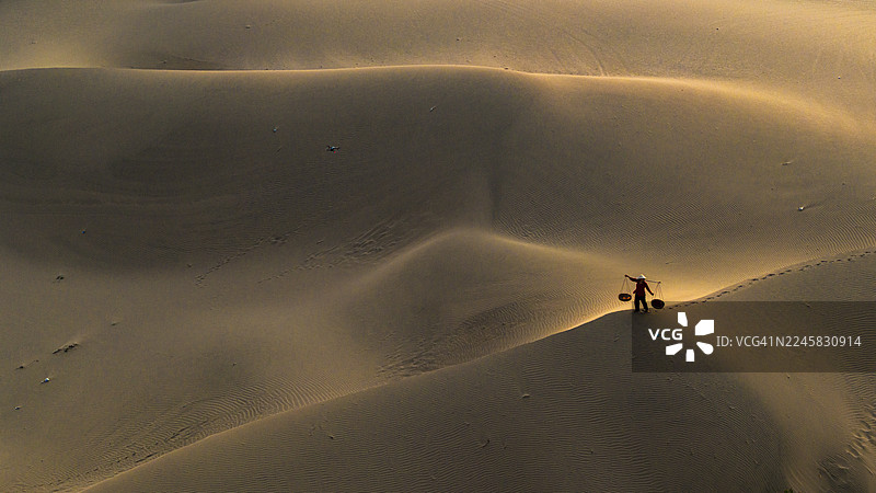 沙丘上工人与背篓的航拍图图片素材