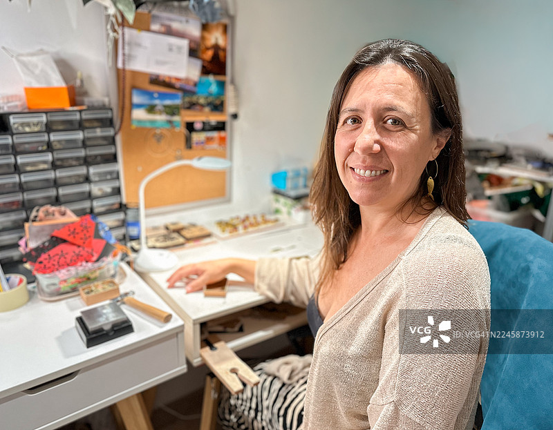 创意工作室里，一位面带微笑的珠宝工匠女性肖像图片素材