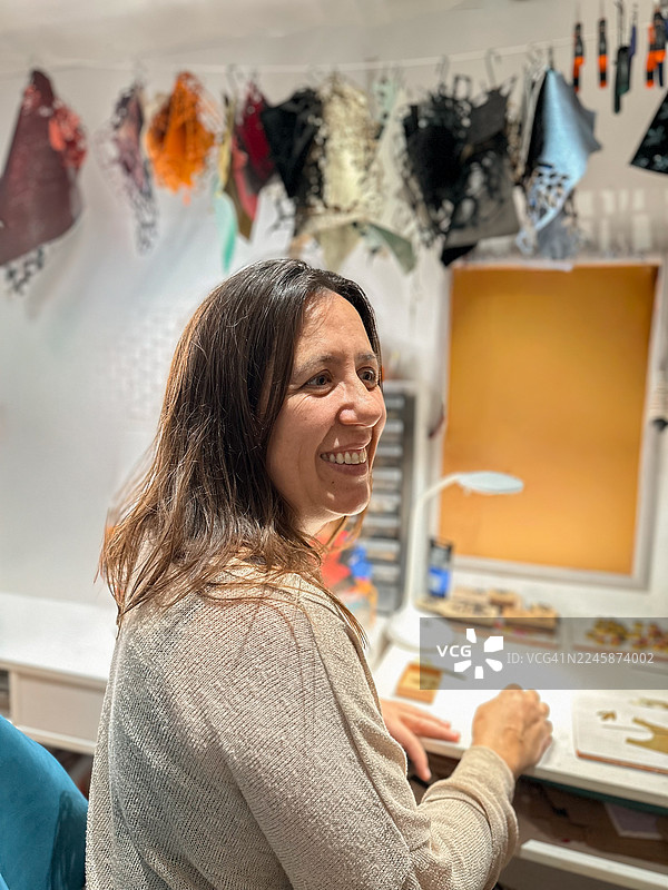 创意工作室里，微笑的珠宝工匠女子侧面肖像图片素材