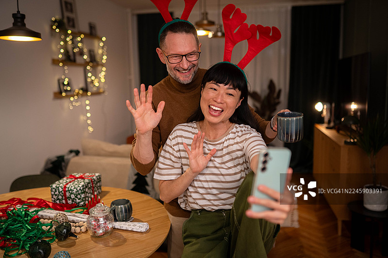 一对情侣在圣诞礼物旁用手机自拍或进行视频通话图片素材