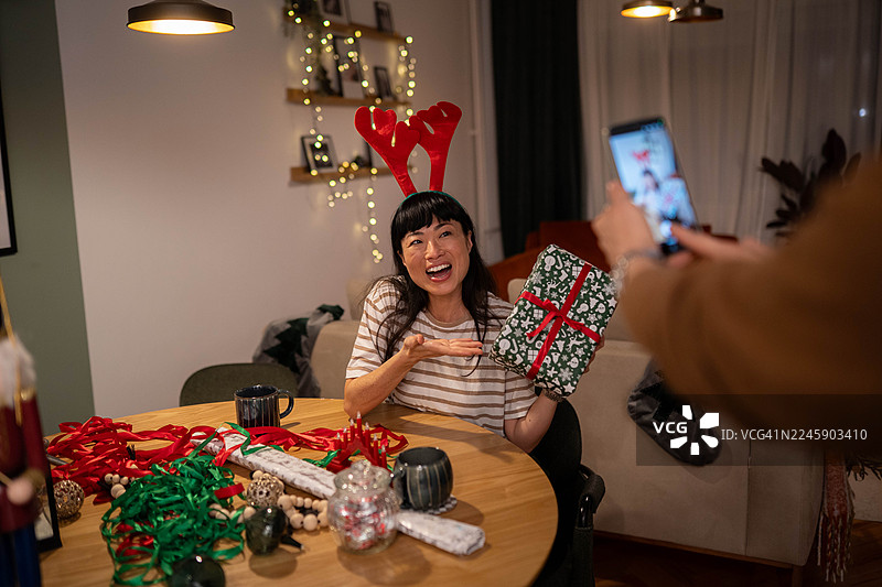 一对情侣在圣诞礼物旁用手机自拍或进行视频通话图片素材