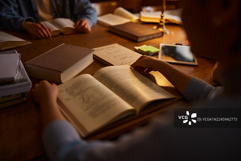 特写镜头：一名学生在阅读书籍，无法辨认其身份。图片素材