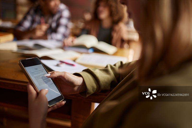 特写：一名女学生在课堂上使用手机。图片素材