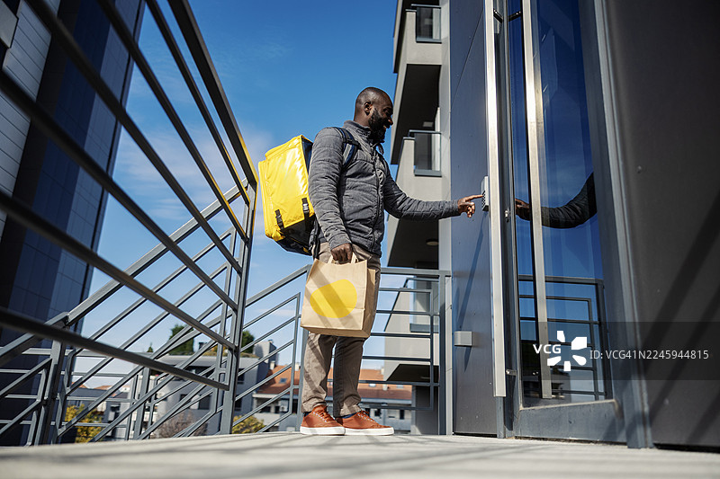 送餐员按门铃以递送食物订单图片素材
