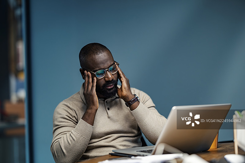 疲惫不堪的商人在办公室办公桌前因过度劳累而头痛图片素材