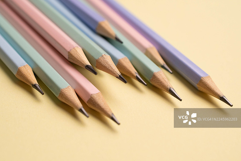 淡黄色背景上的叠放的铅笔图片素材