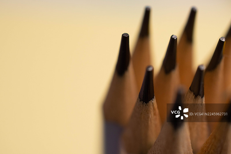 彩色铅笔堆叠在粉黄色背景上图片素材