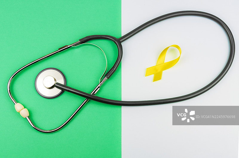 带有听诊器的缎面黄丝带，背景为绿色和白色。图片素材