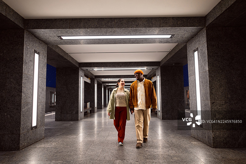 年轻混血情侣牵手漫步在柏林地铁站，深情对视图片素材