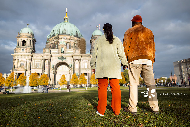 情侣在情人节期间参观柏林大教堂，背后是他们站在一起的背影图片素材