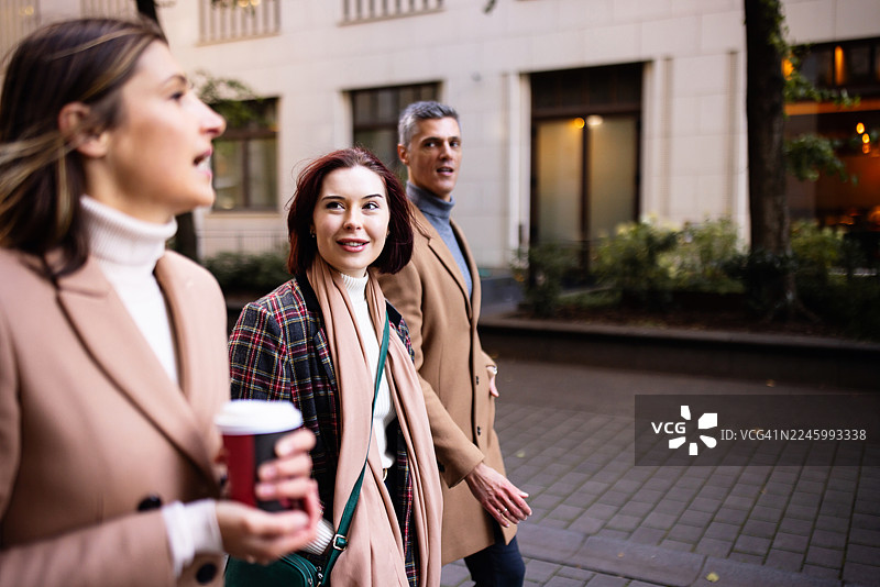 穿着暖和的商务人士在柏林边走边谈，并带着咖啡上班图片素材