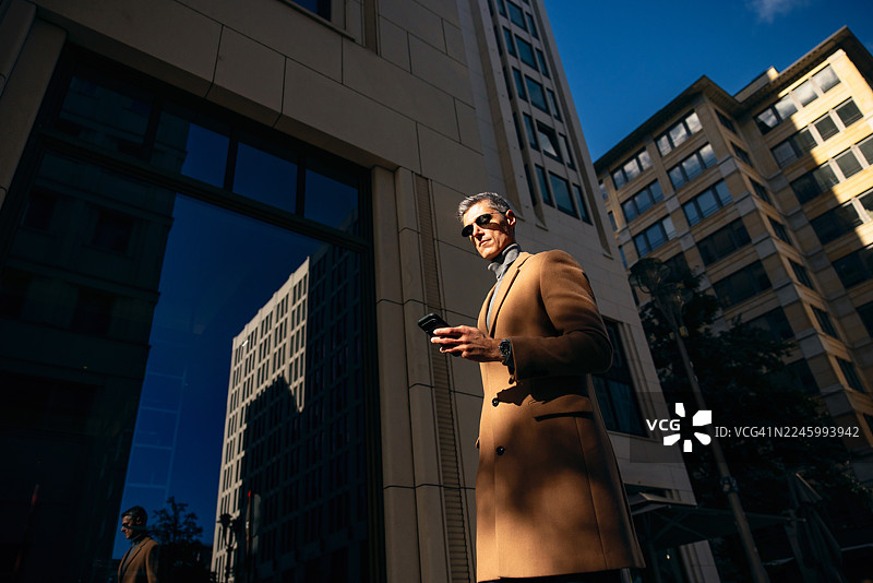 身着太阳镜的商务男士在柏林户外使用智能手机图片素材
