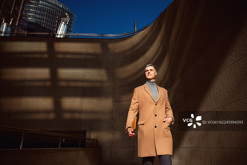 一位穿着时尚外套的成熟商务人士在柏林户外行走图片素材