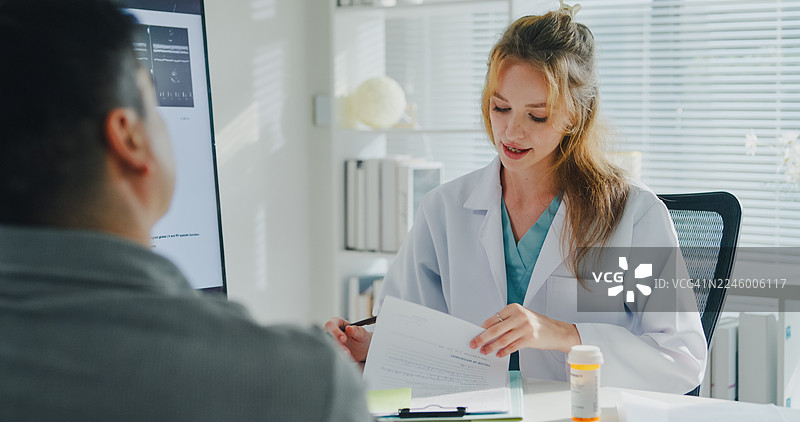 年轻女医生在诊所办公室向成年男患者解释药物处方。医疗保健概念。图片素材