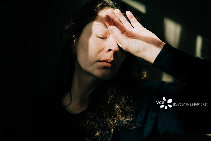 疲惫不堪的女子用手捂着眼睛，头痛欲裂图片素材