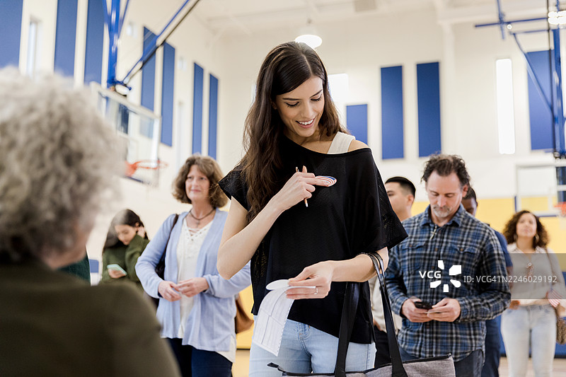 一位女士在投票后自豪地展示她的“我已投票”贴纸。图片素材