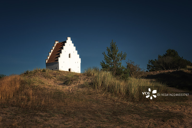 丹麦格伦的白色历史教堂，背景是深蓝色天空，坐落于沙丘之上图片素材