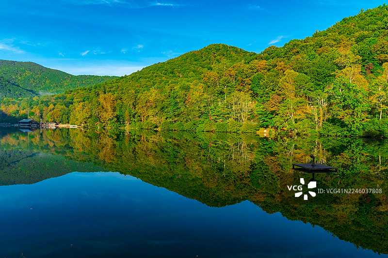 秋日宁静的森林山峦倒映在平静的湖水中，天空湛蓝，美国布莱尔斯维尔图片素材