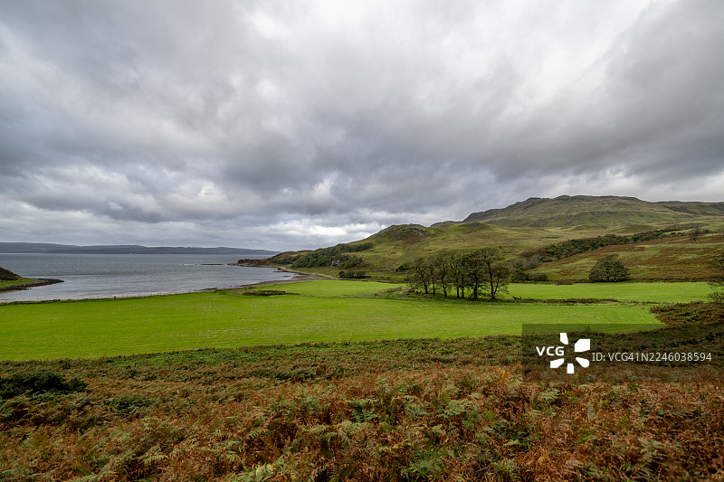 苏格兰高地，英国，阿德斯利尼什，戏剧性的多云天空笼罩着宁静的海湾，周围环绕着郁郁葱葱的绿色田野和起伏的山丘。图片素材